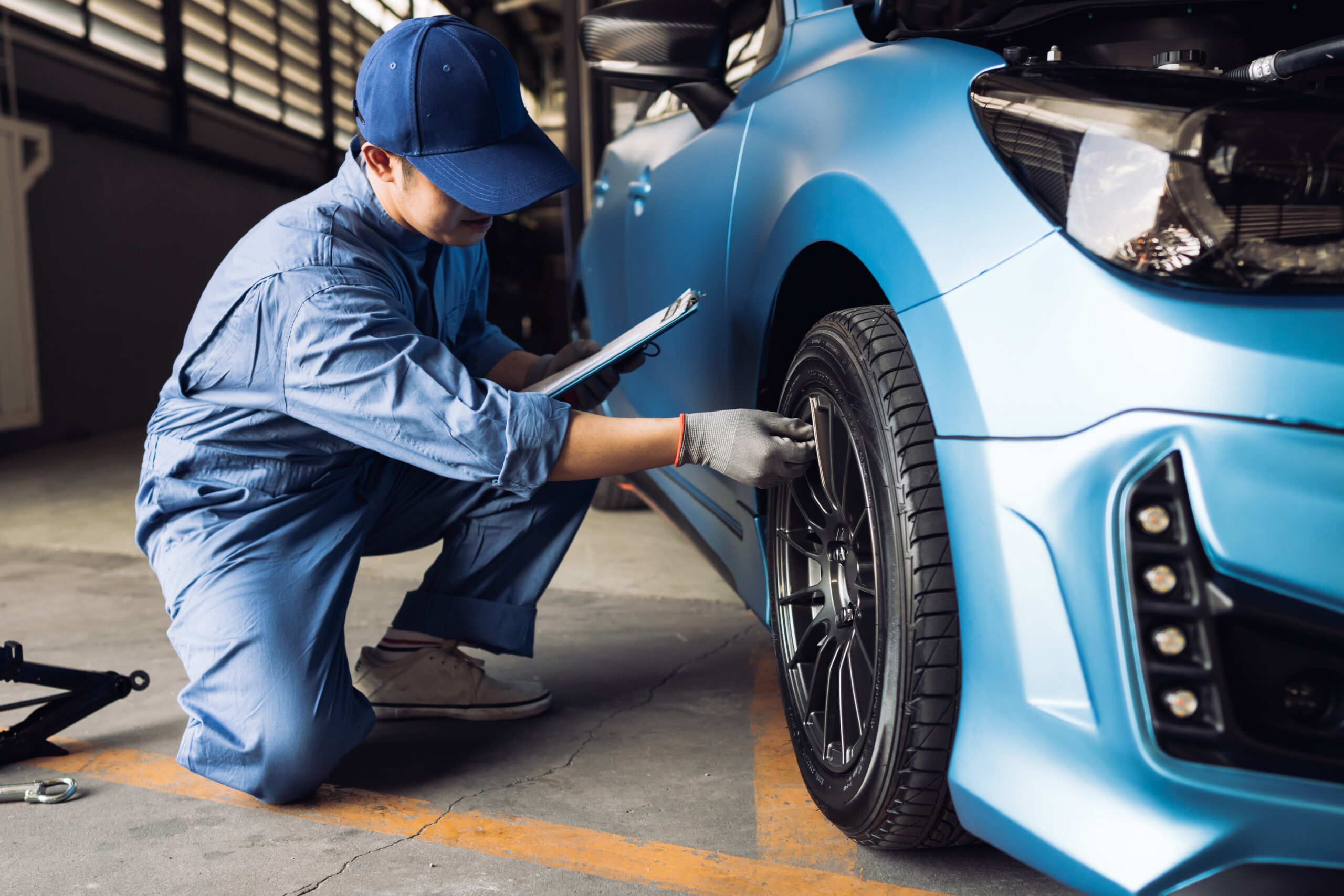 Maintenance male checking tire service via insurance system at garage, Safety vehicle to reduce accidents before a long travel, Blue car of man transportation lifestyle